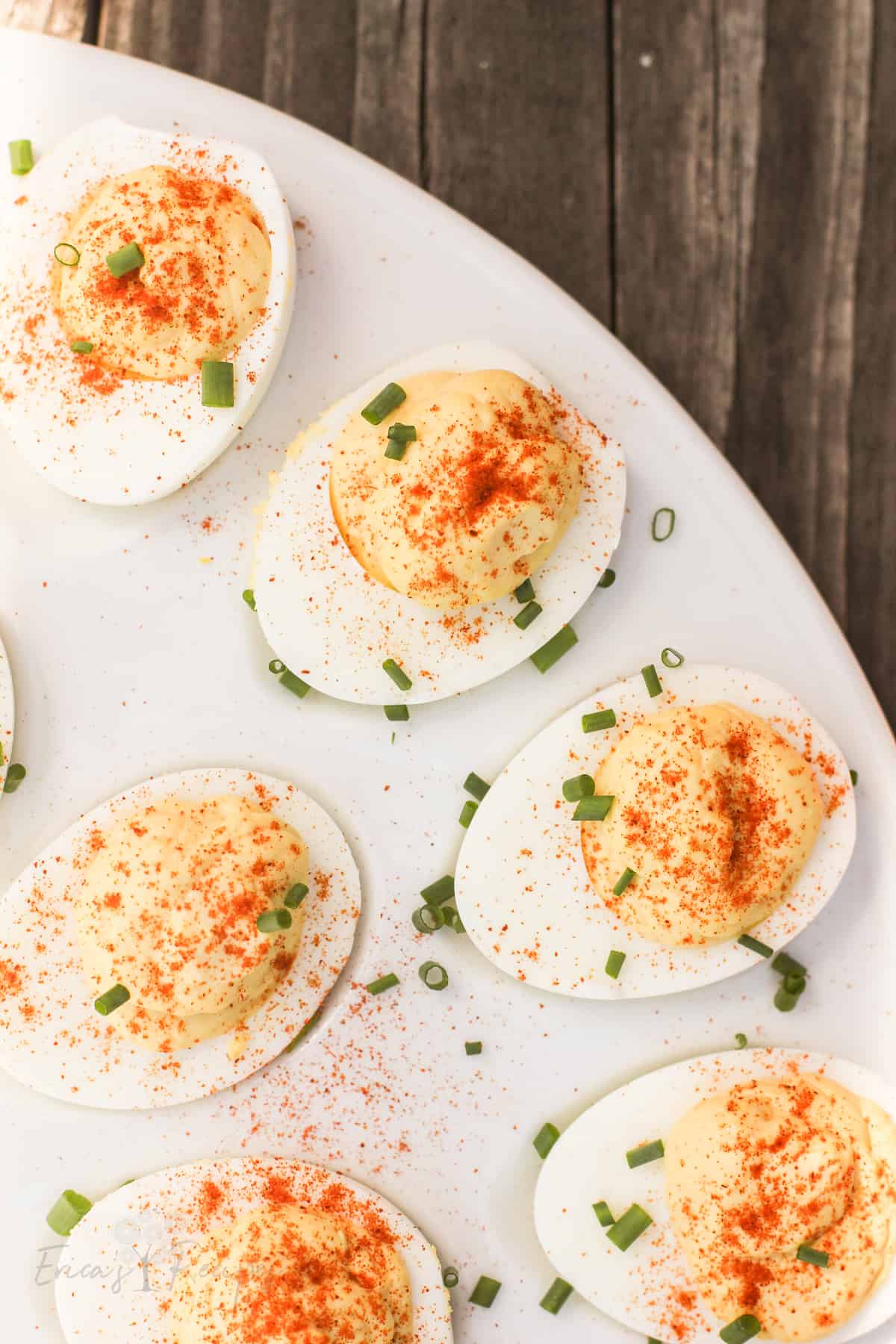 top down view of deviled eggs topped with chives on a white serving platter