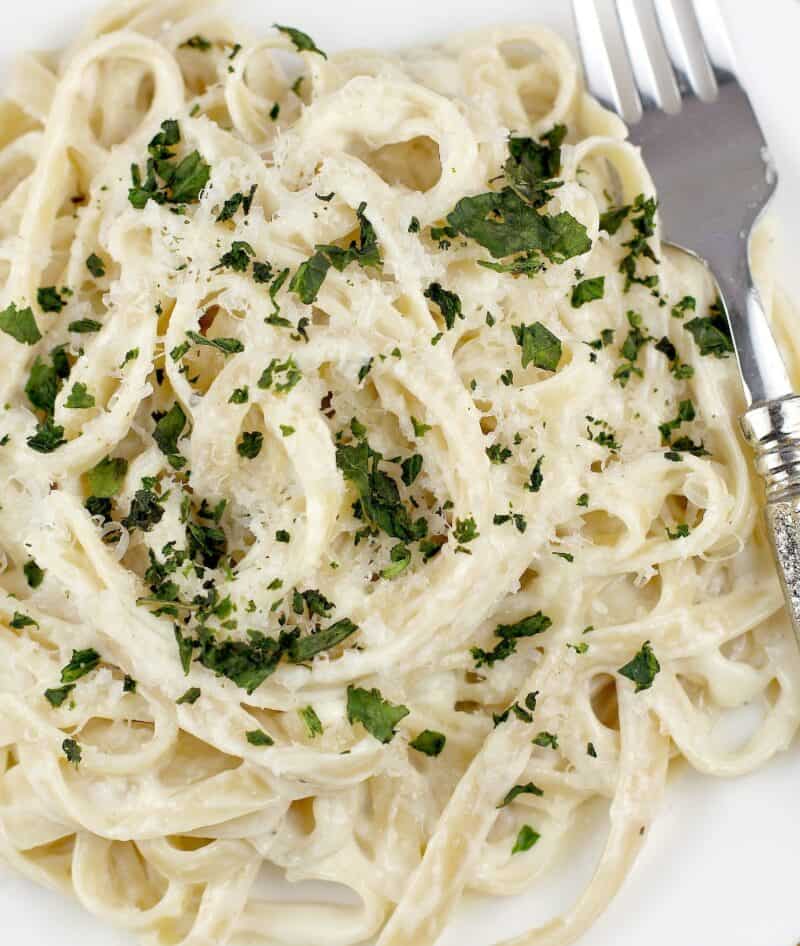pasta in white sauce on a white plate with a fork