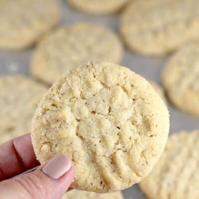 a hand holding up a potato chip cookie. other cookies are visible in the background on a bake sheet