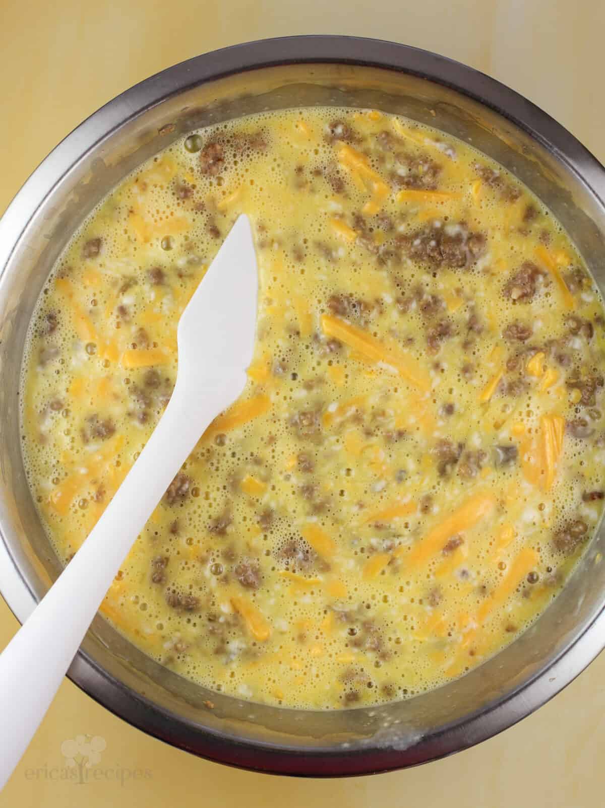 casserole ingredients mixed in a metal bowl with white rubber spatula