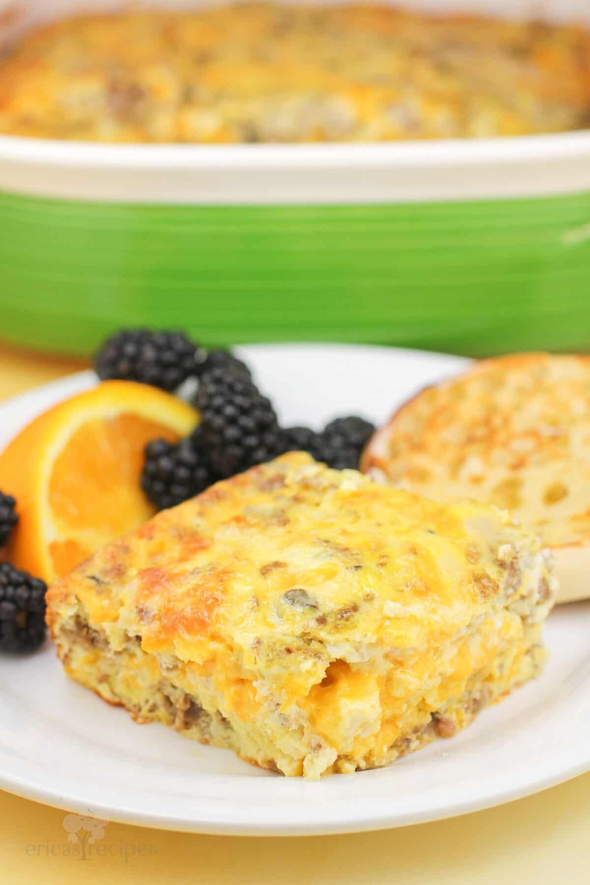 sausage egg cheese casserole on white plate with fruit garnish