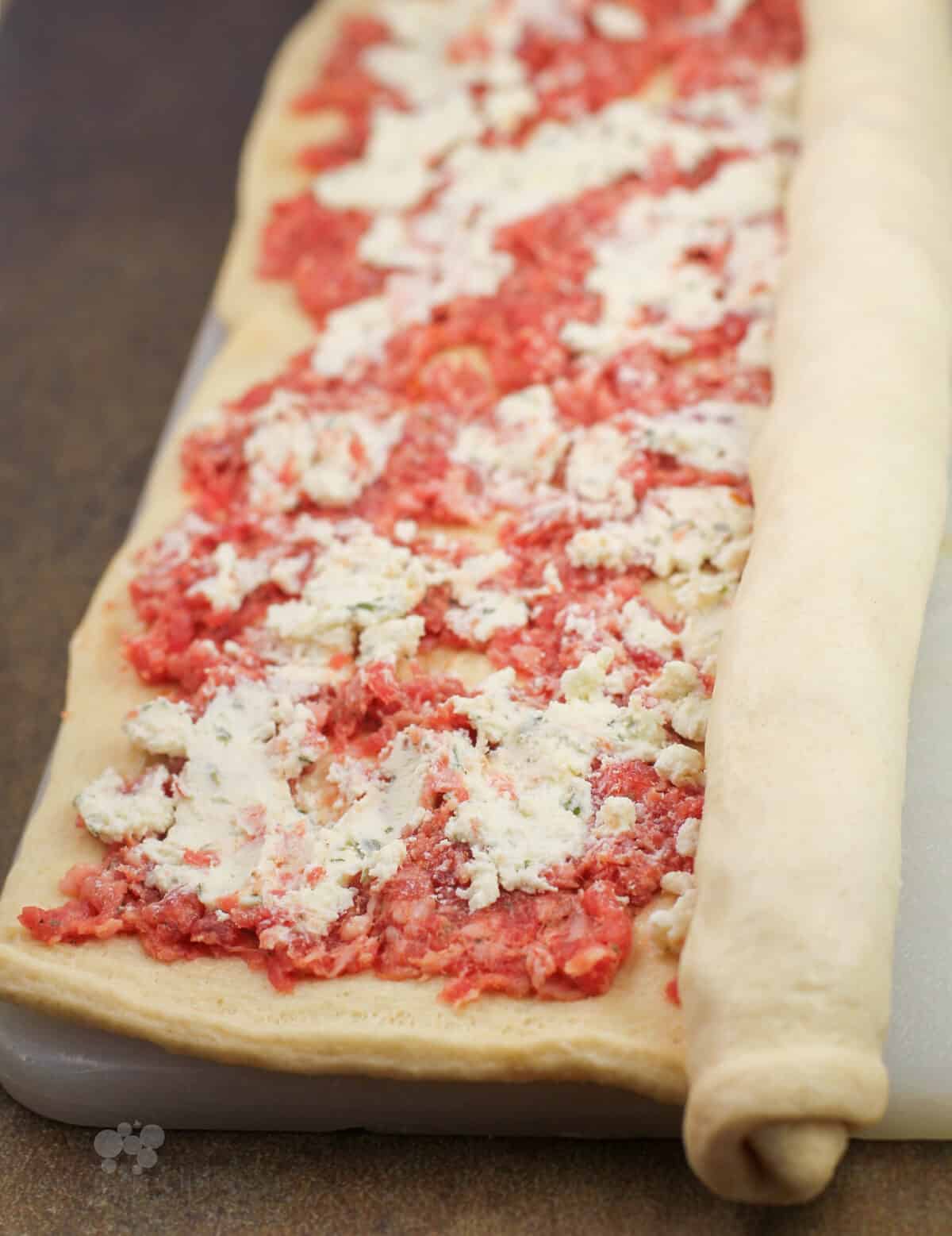 rolling up dough over sausage and Boursin