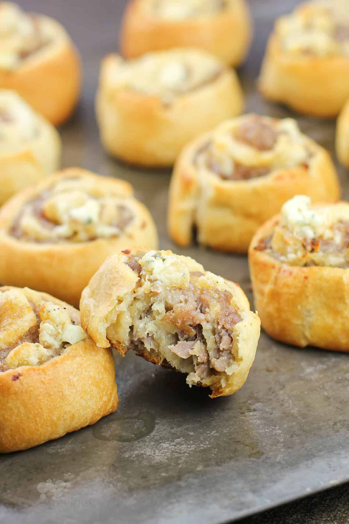 sausage pinwheels on bake sheet, one with bite taken out