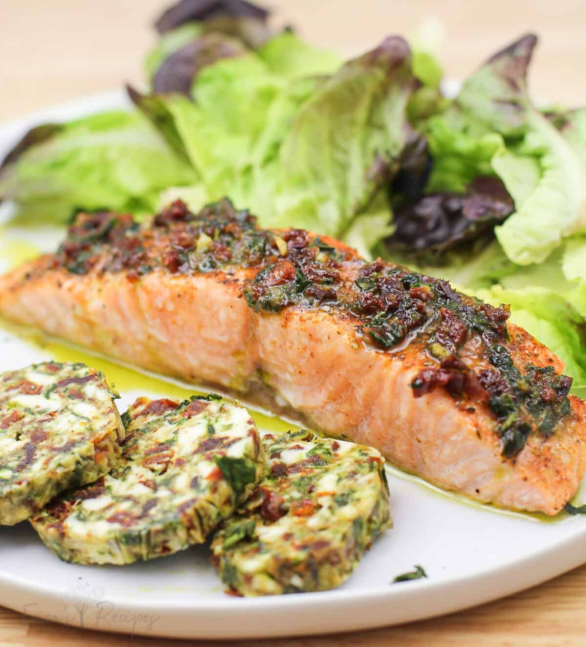 cooked salmon on white plate; prepped recipe in foreground