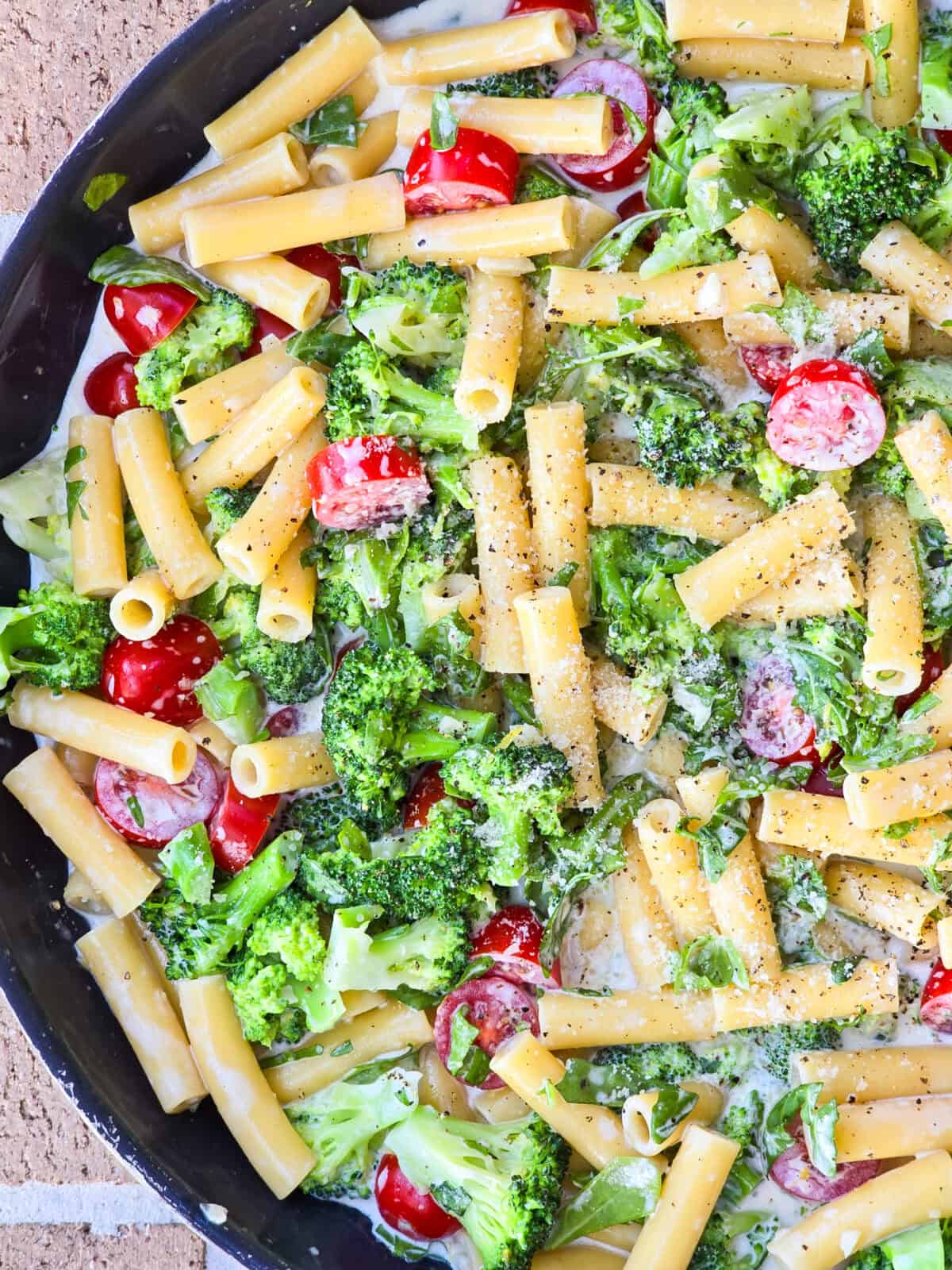 top down view into skillet with prepared arugula and broccoli pasta