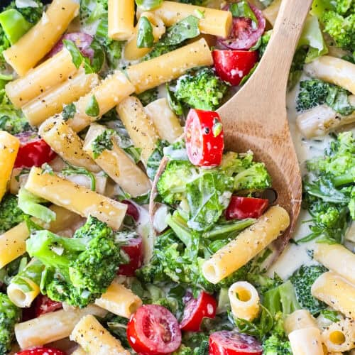 prepared lemon pasta with arugula and broccoli in large skillet with wood spoon