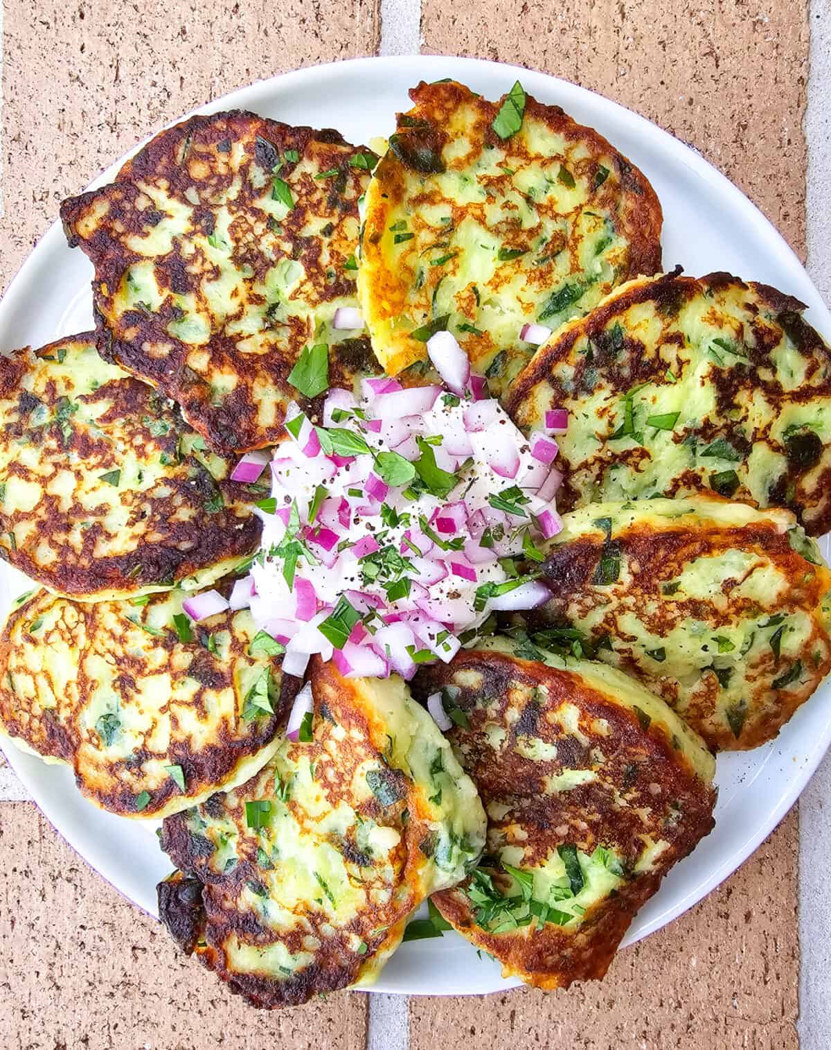 prepared instant mashed potato cakes on plate with sour cream and red onion in the center