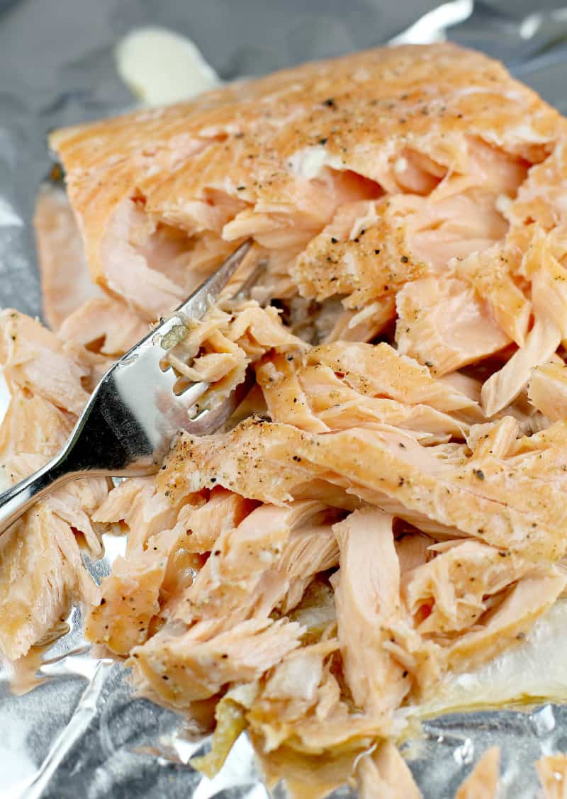 flaked cooked salmon with a fork on a bake sheet