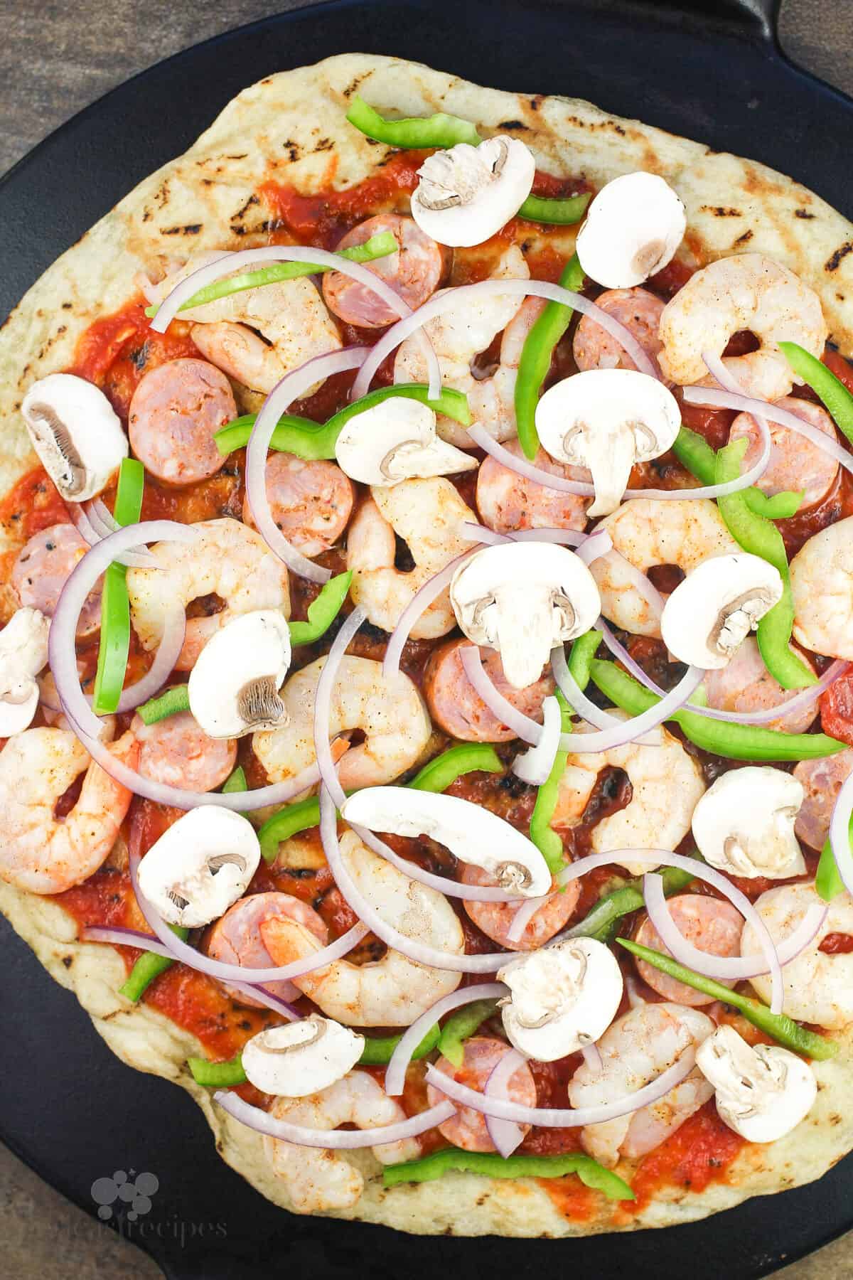 pizza toppings on crust before adding cheese