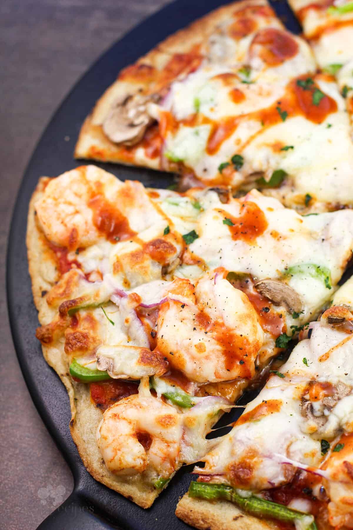 slice of cajun pizza on black surface
