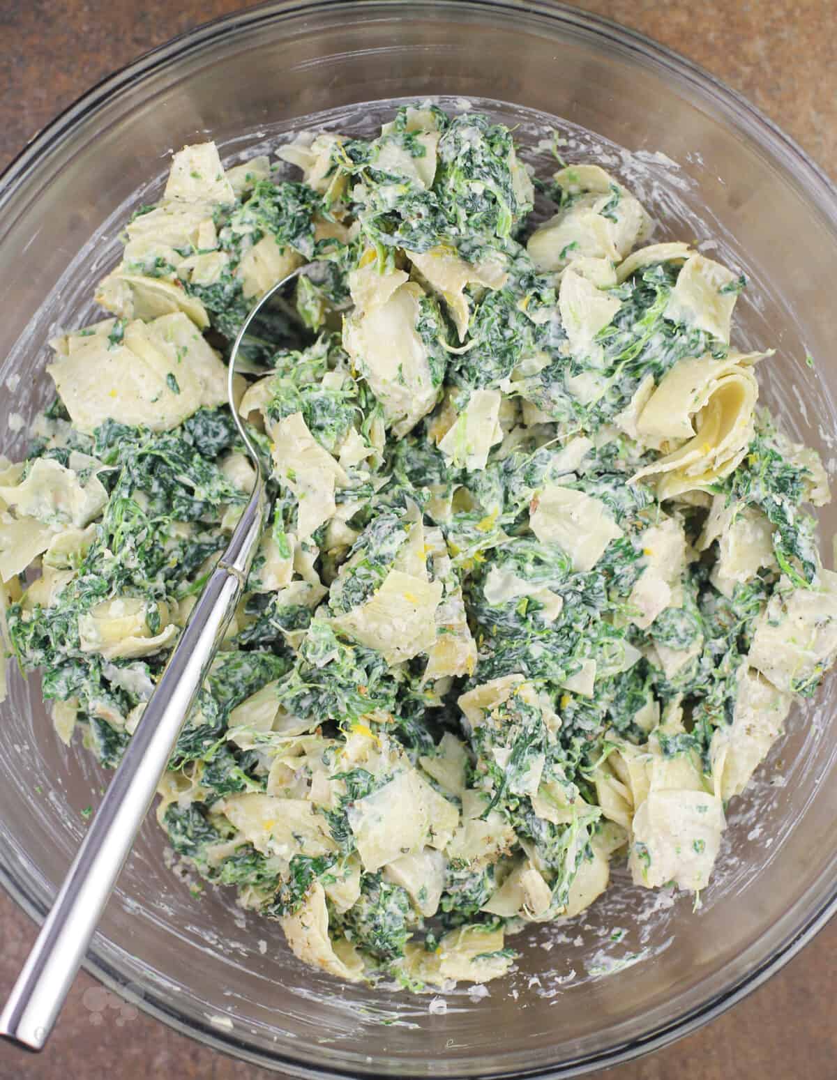 spinach artichoke dip in a glass bowl with fork