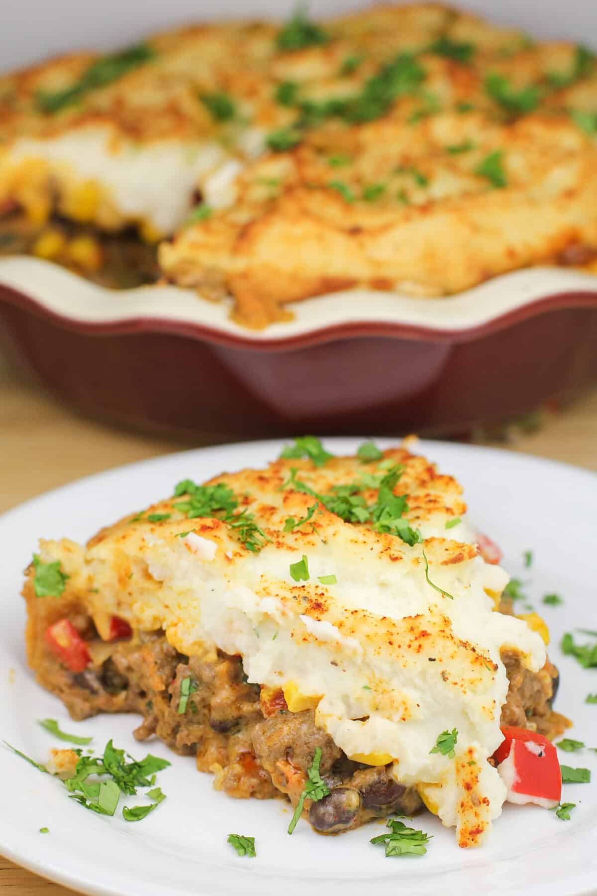 serving of prepared Mexican shepherd's pie on white plate; red pie plate in the background