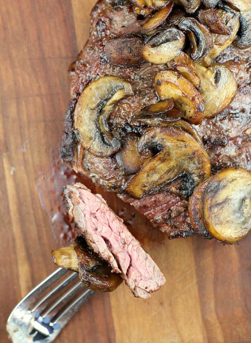 top view of finished steak cut with fork holding a piece to show doneness