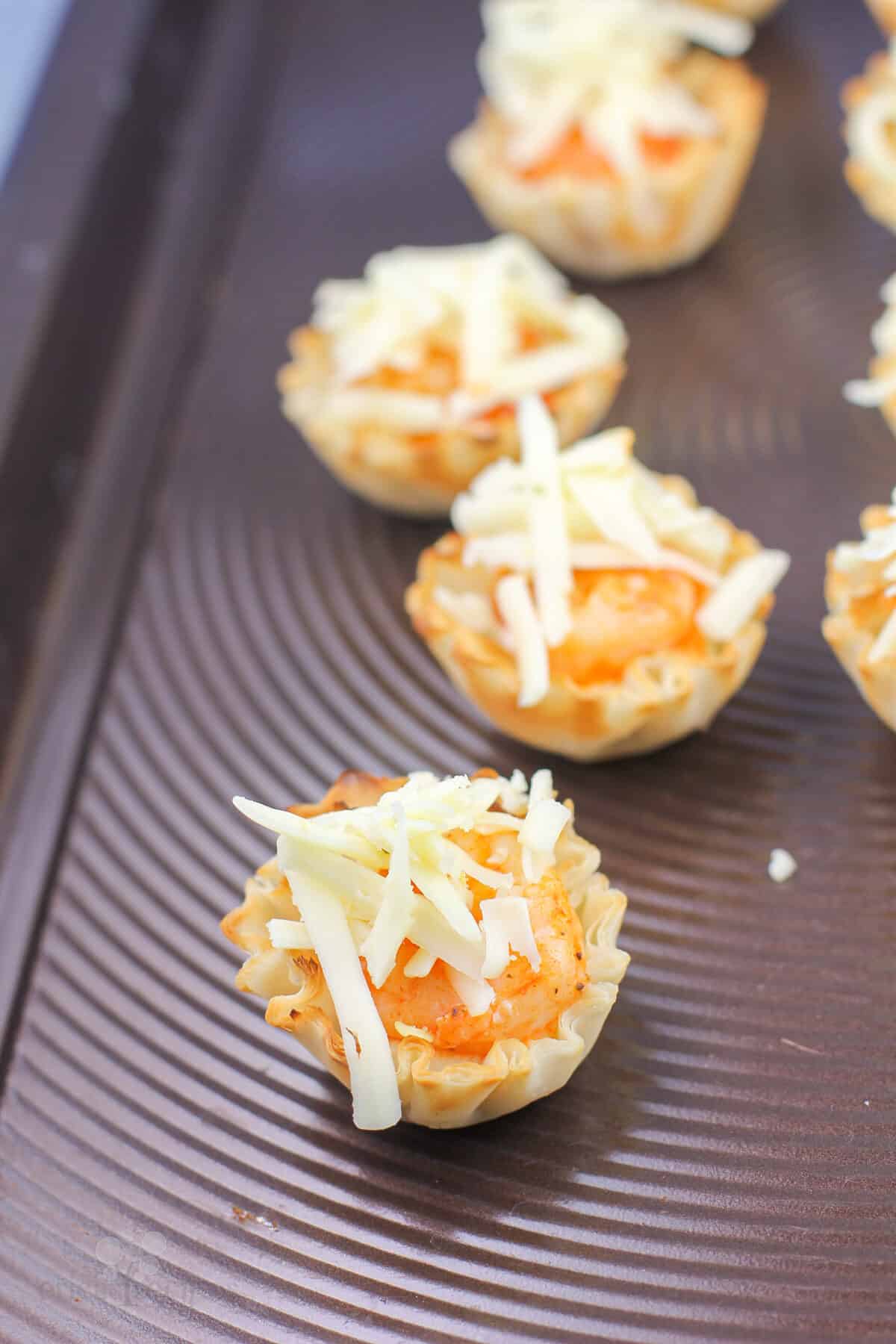 filled phyllo shells topped with cheese before cooking