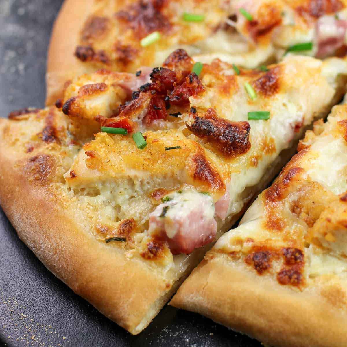 slice of chicken cordon blue pizza on black pizza stone