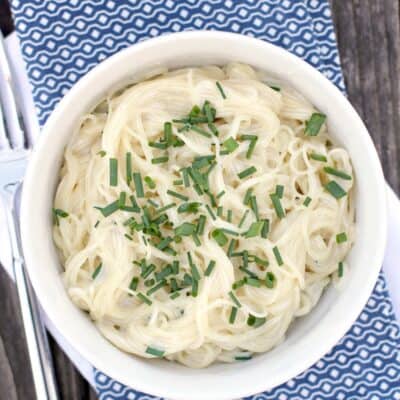 top down view into bowl with pasta on napkin by a fork