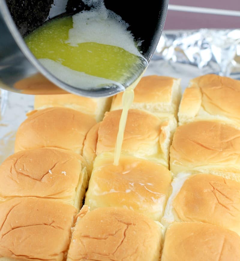 butter being poured over the Hawaiian roll turkey sliders