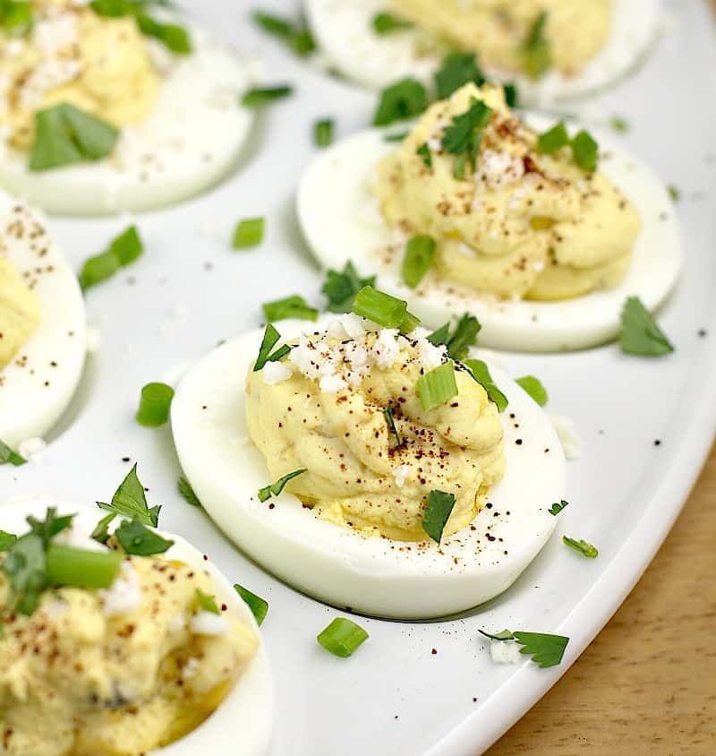Mexican street corn deviled eggs on a white plate, on a cutting board