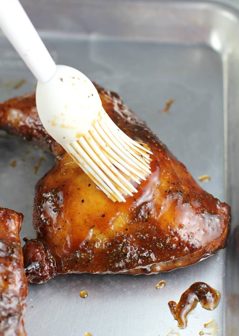maple bourbon glaze being mopped on a piece of cooked chicken