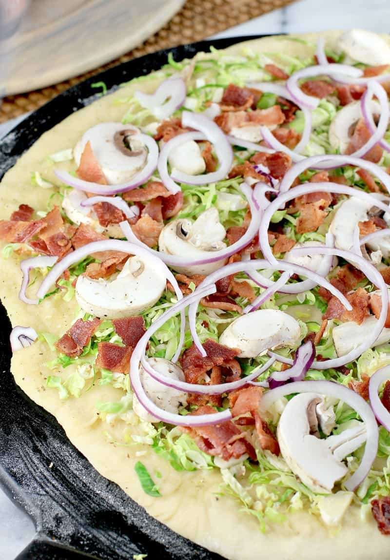 raw toppings layered on pizza dough