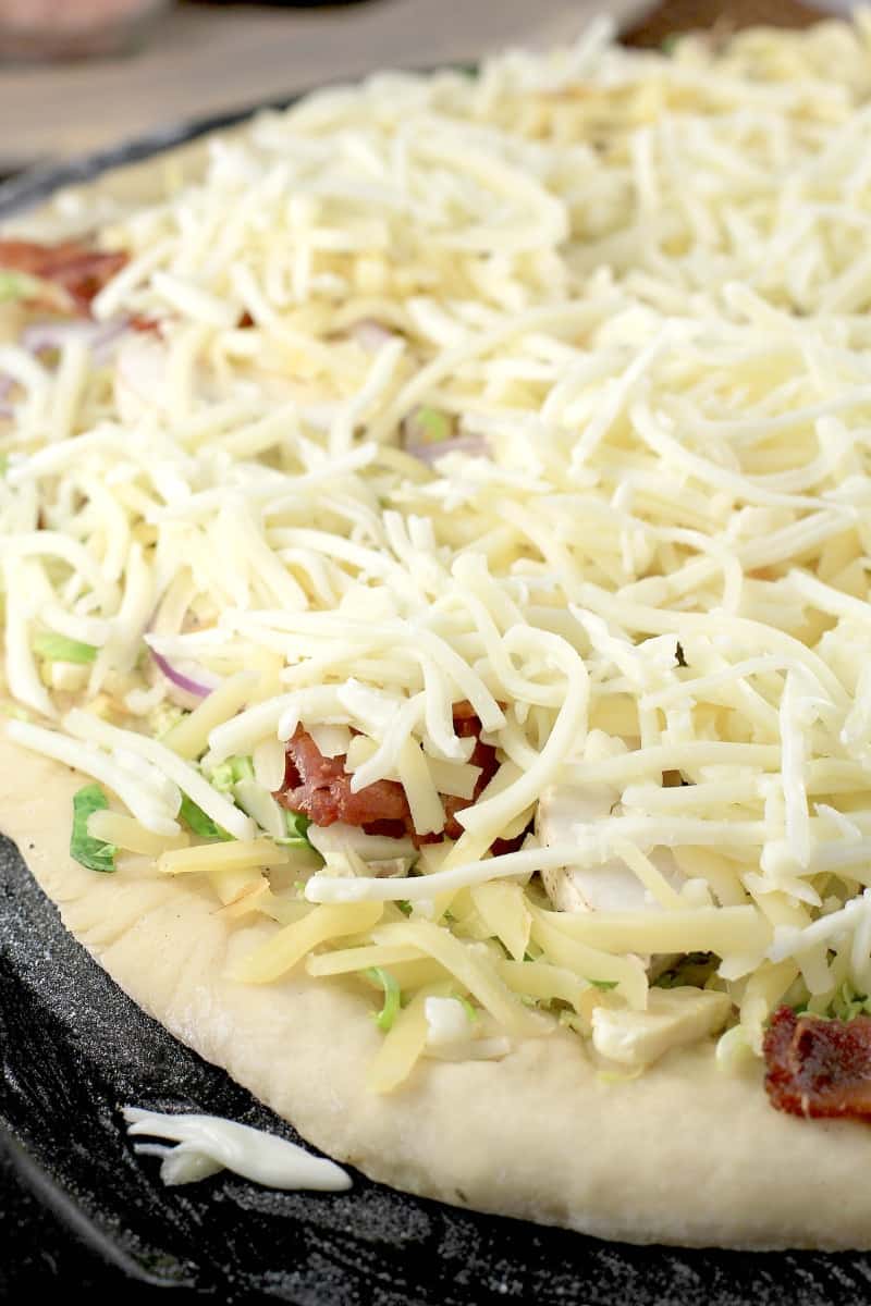 cheeses layered on pizza before cooking