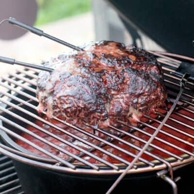large loaf of smoked ground beef on grill grate in Big Green Egg with temperature probes sticking out