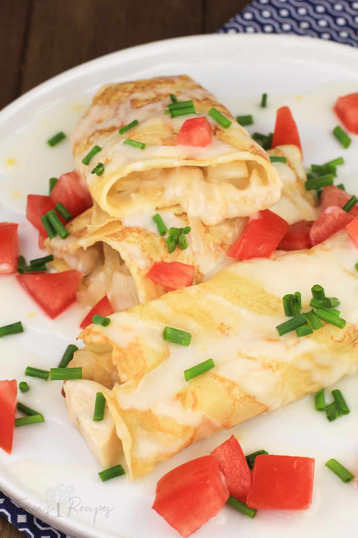 crepes with chicken and potato on white plate, one cut open to show filling