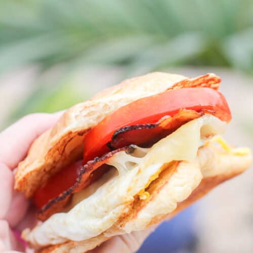 hand holding a croissant breakfast sandwich