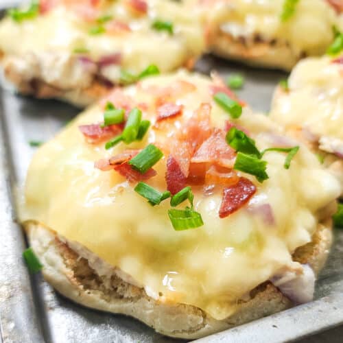 close, side view of open faced tuna melt on bake sheet topped with bacon and chives