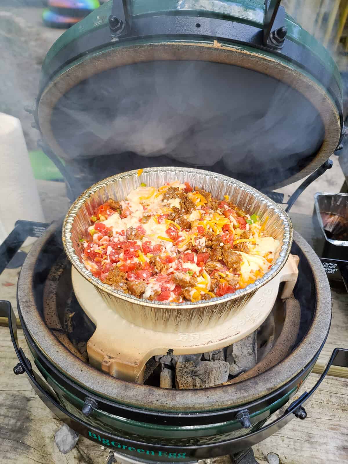 open big green egg with queso smoking on plate setter