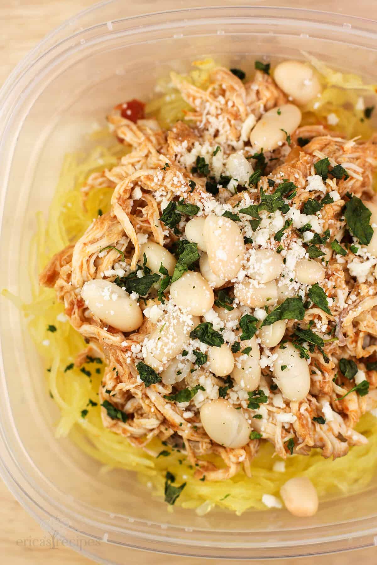 top down view into plastic container with prepared chicken over spaghetti squash