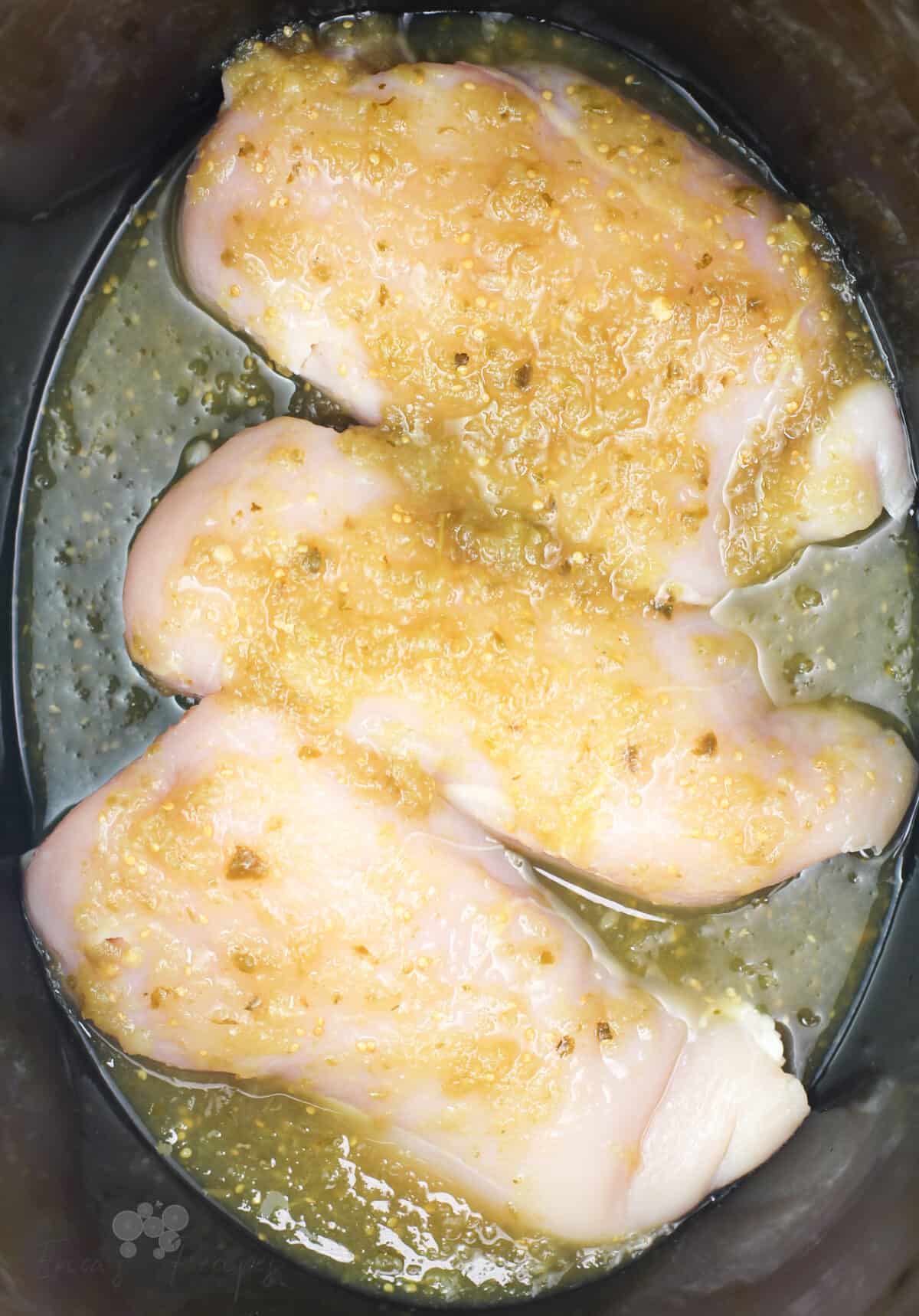 raw chicken breasts in crock pot topped with salsa verde
