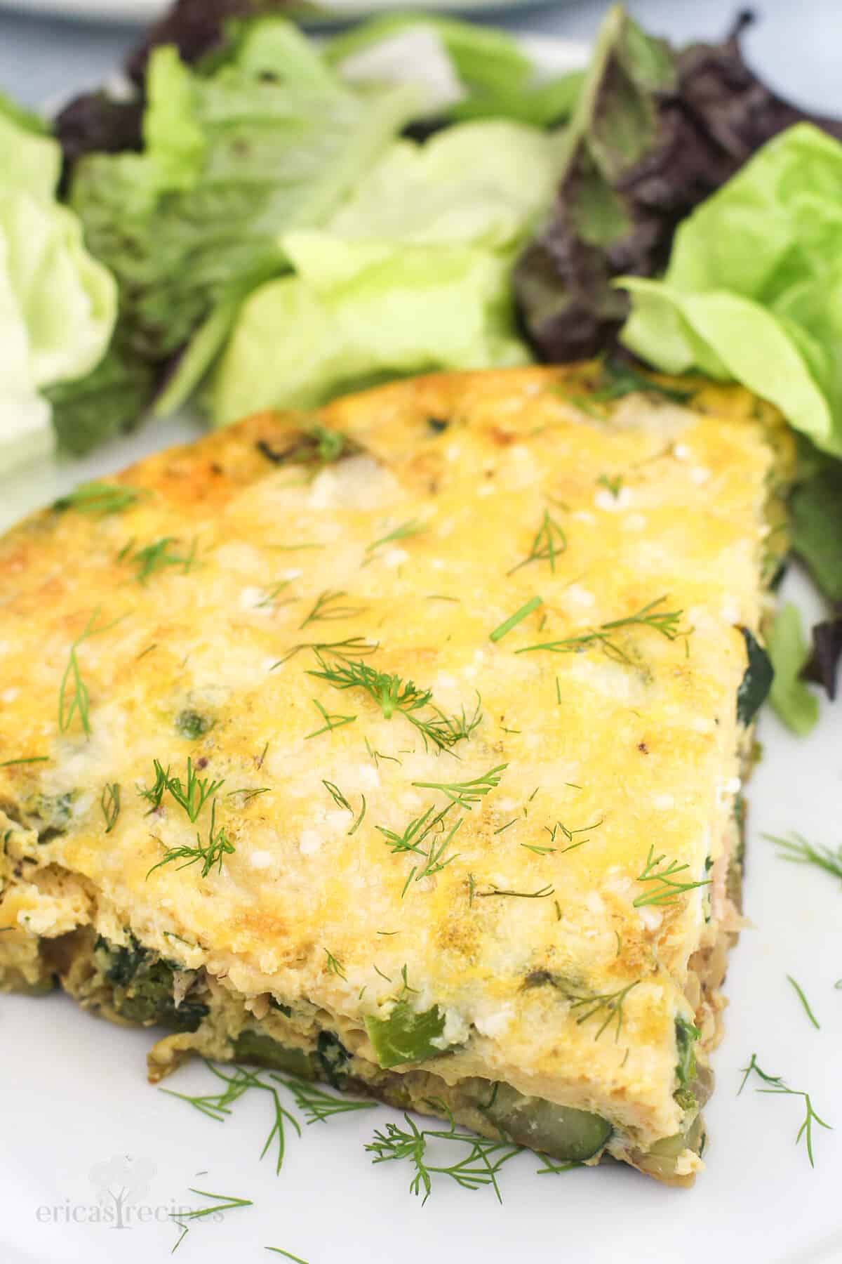 portion of vegetable frittata on white plate with salad