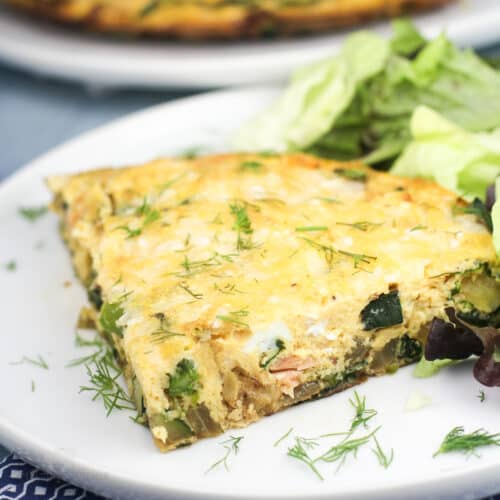 portion of vegetable frittata with smoked salmon on white plate