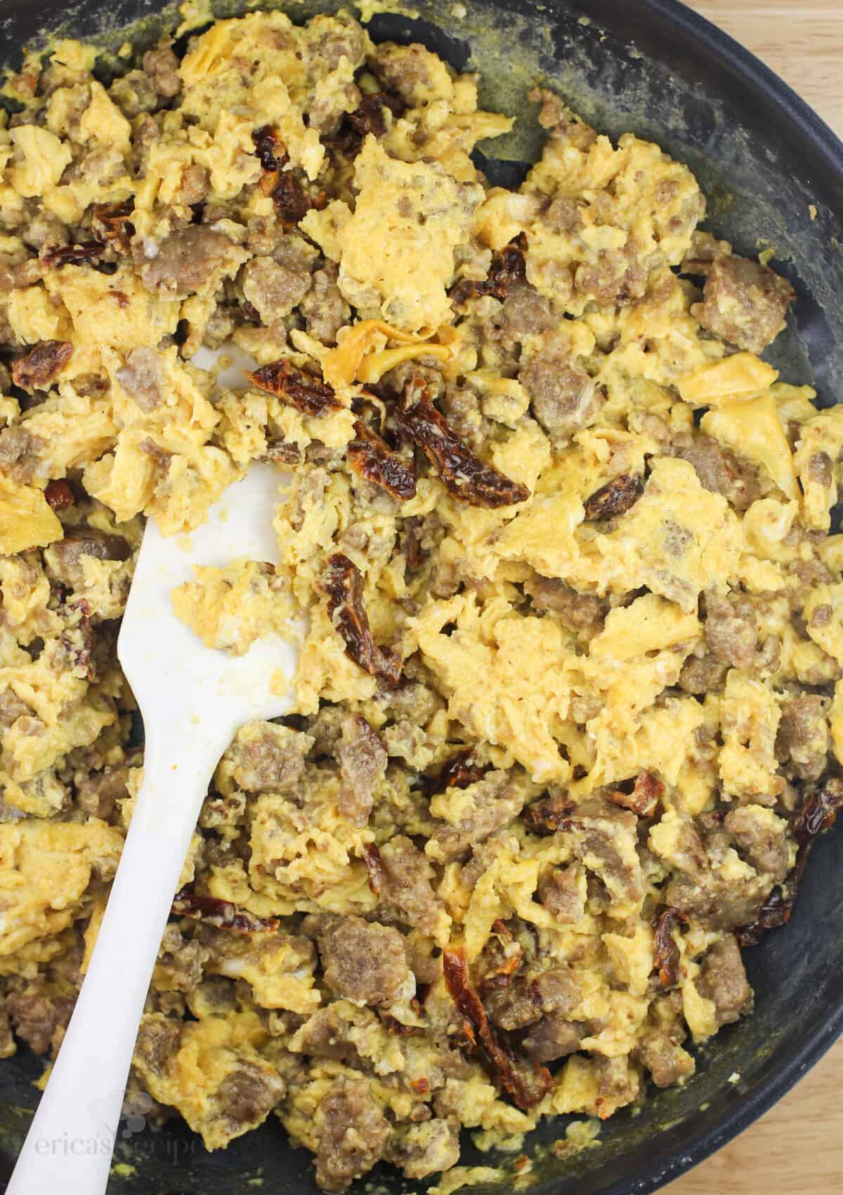 egg and sausage crepe filling in skillet with white rubber spatula