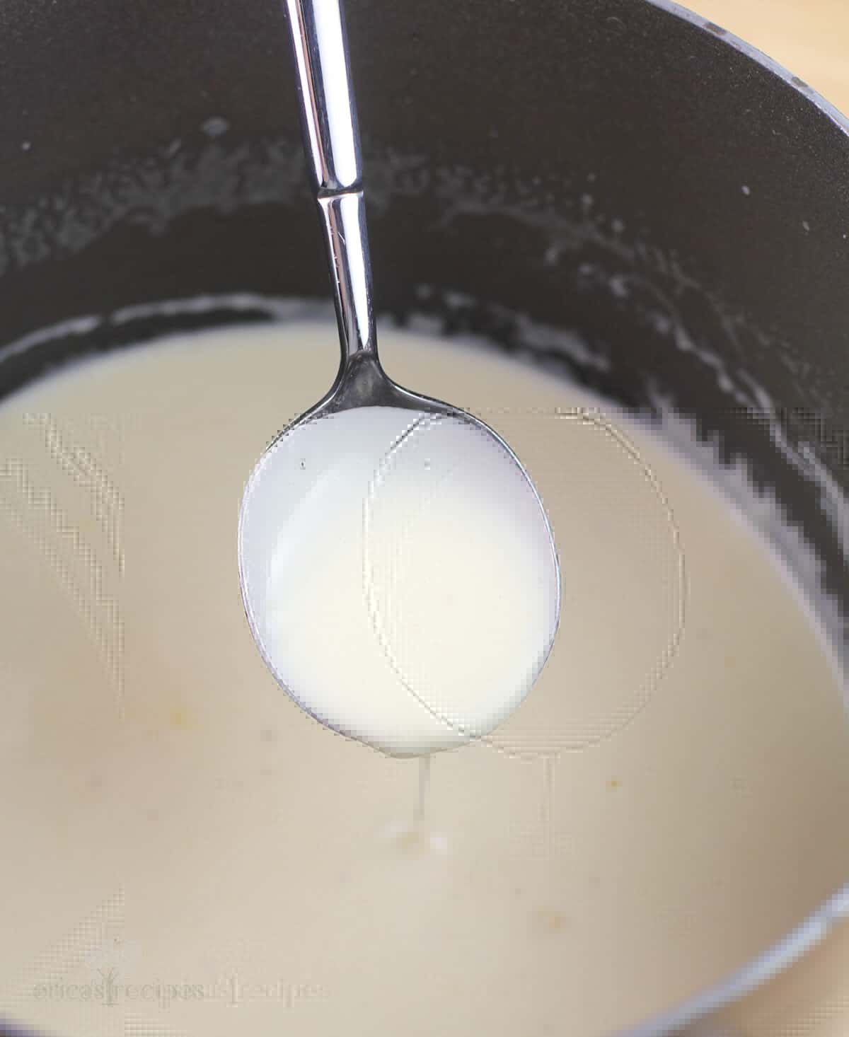 spoon holding maple bechamel to show thickened consistency