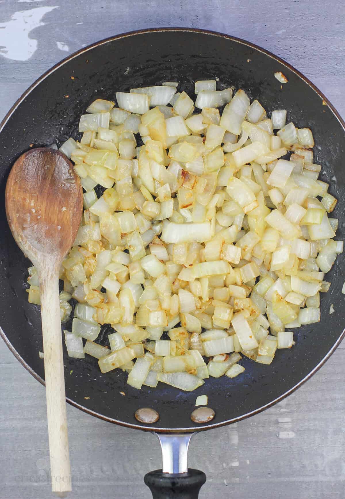 onion and garlic in skillet with wood spoon