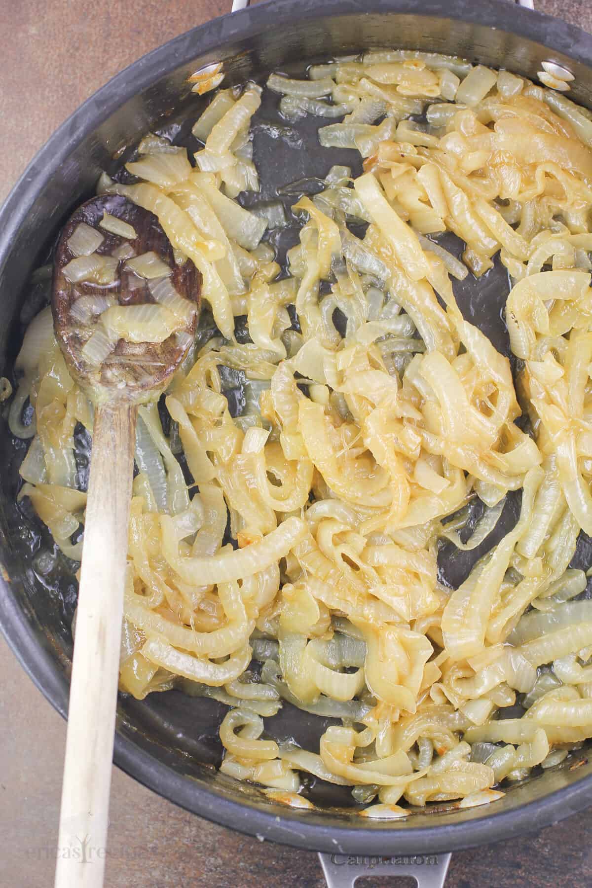 prepared bourbon caramelized onions in skillet with wood spoon