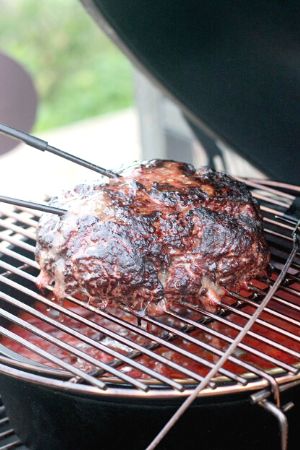large ball of meat on grill grate over pot of chili in big green egg cooker