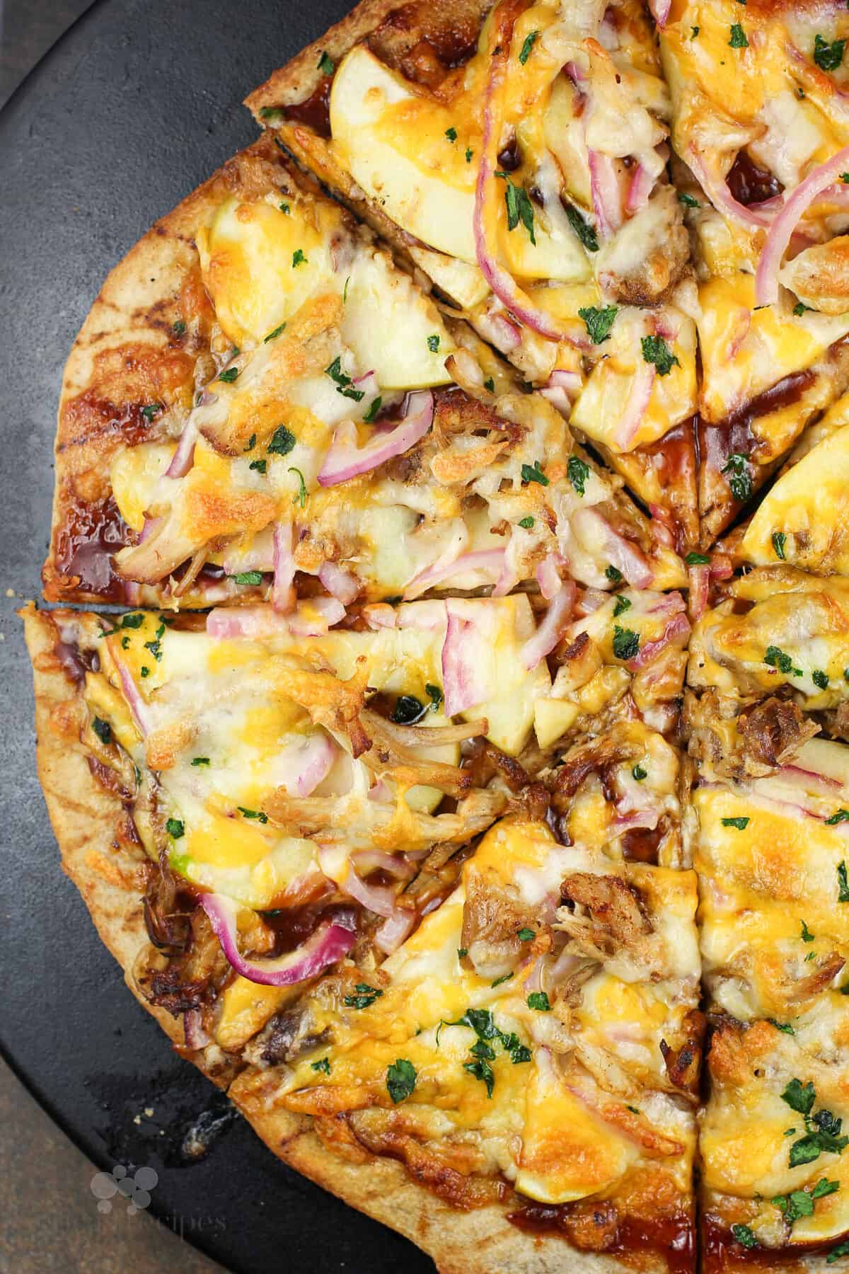 sliced pizza on black pizza stone.