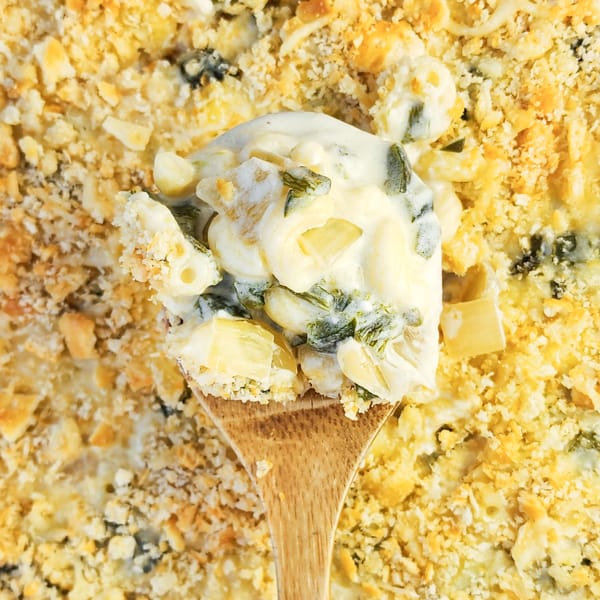 wood spoon holding mac and cheese over casserole
