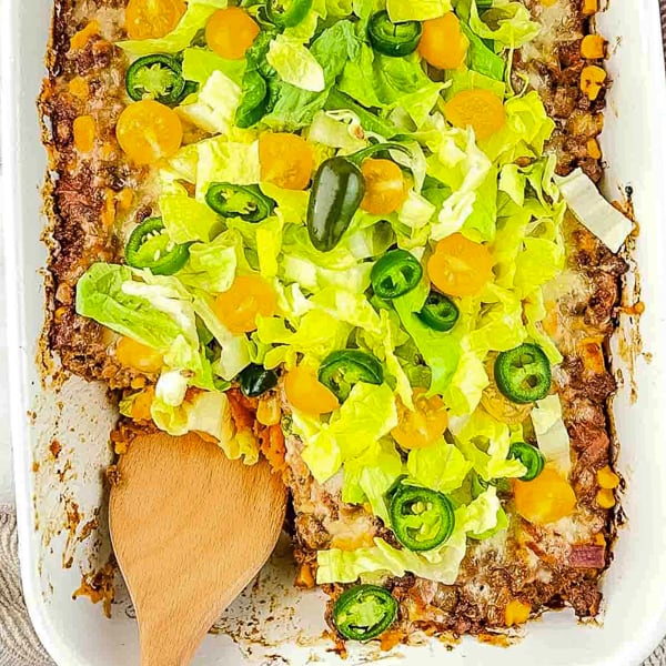 casserole topped with shredded lettuce, diced tomatoes, and sliced jalapeno peppers