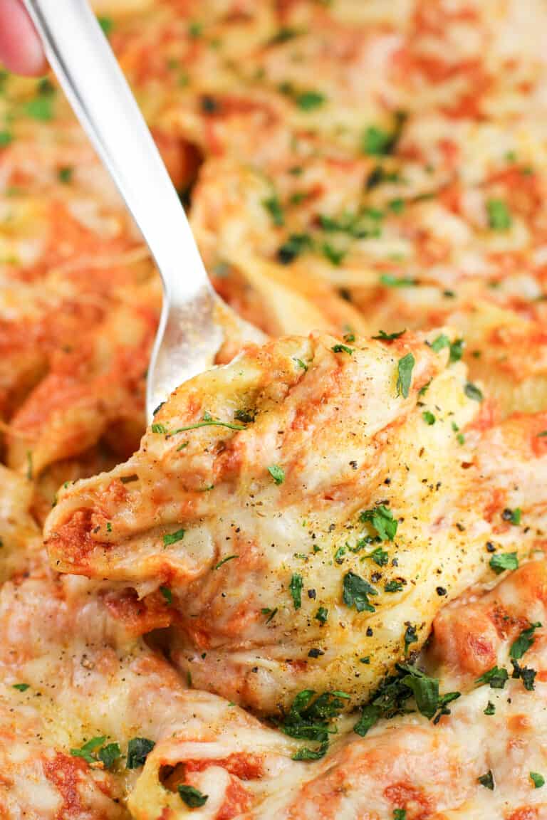 spatula lifting a Cajun Shrimp and crab stuffed shell in casserole dish