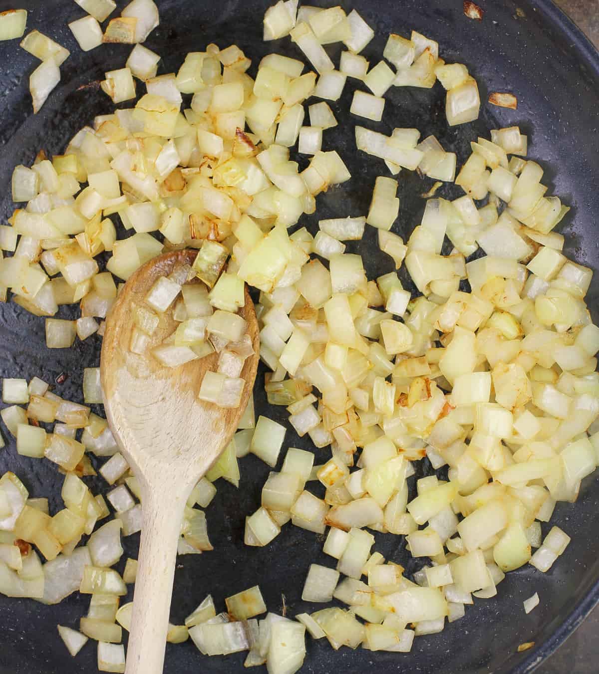 onions cooked in skillet with wood spoon
